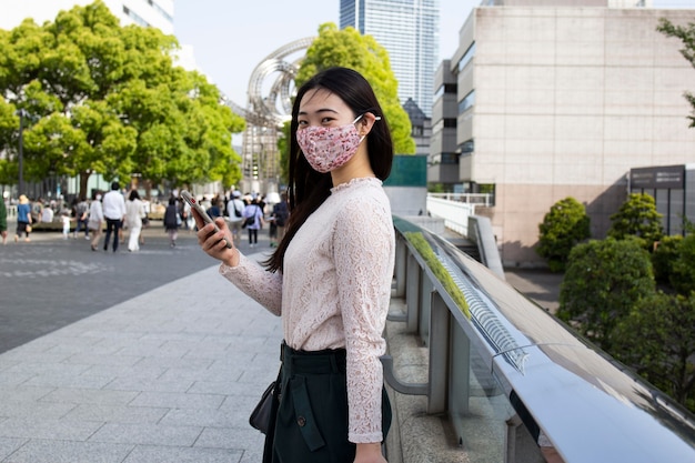 Zdjęcie piękna japonka z maską medyczną w miejskim otoczeniu