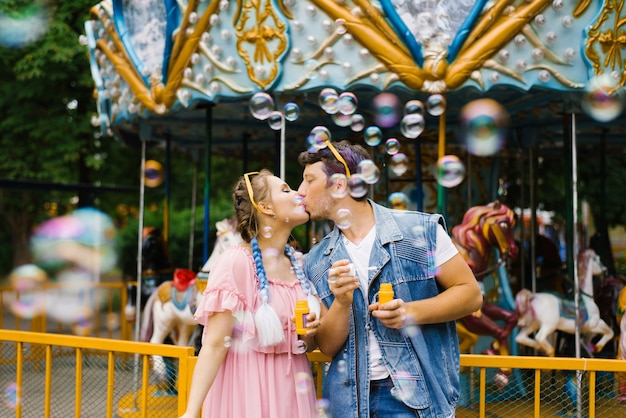 Zdjęcie piękna, jasna, wesoła, romantyczna para zakochanych, ciesz się bańkami mydlanymi w parku rozrywki i całuj