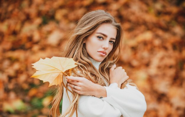Piękna jesienna kobieta z liśćmi na jesiennym tle przyrody