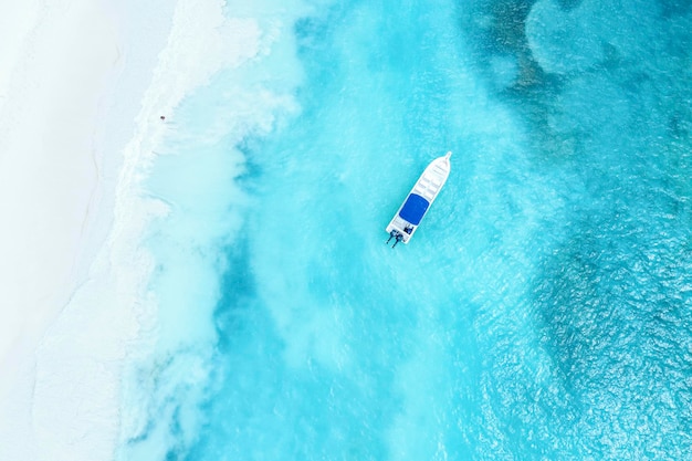 Piękna karaibska plaża na wyspie Saona, Dominikana. Abstrakcyjny widok z lotu ptaka na tropikalny idylliczny letni krajobraz z błękitną wodą morską, białym piaskiem i pojedynczą łodzią