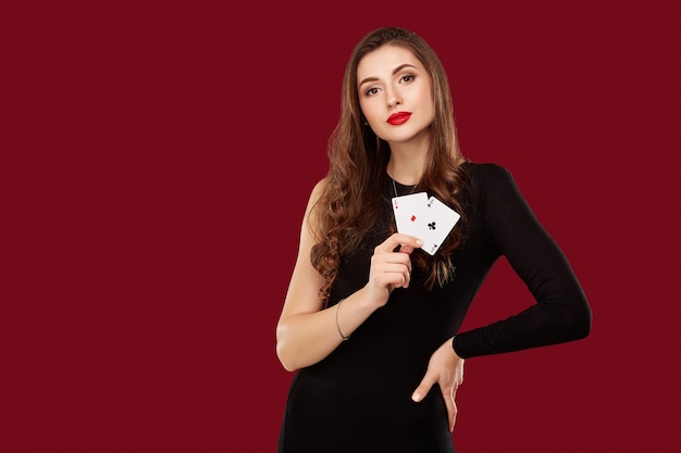 Piękna kaukaska kobieta w czarnej sukience z kartami do gry w pokera w kasynie