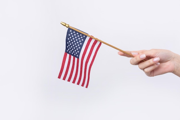 Piękna kobieca ręka trzyma amerykańską flagę na białym tle