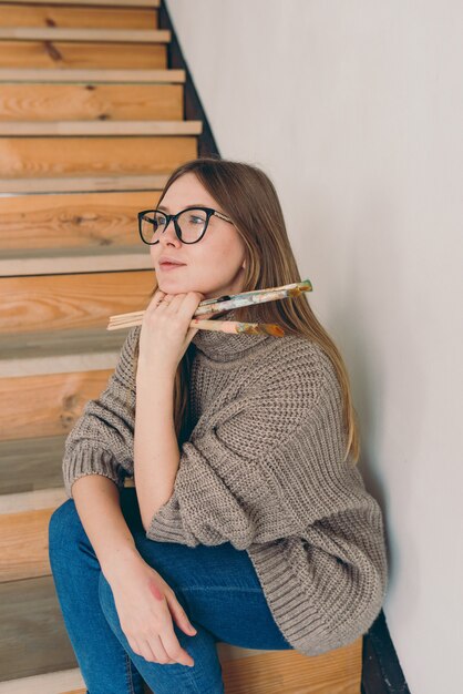 Piękna Kobieta Artystka W Okularach I Casual, Siedząca Na Schodach Ze Szczotkami