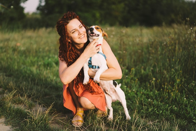 Piękna kobieta bawi się ze swoim psem jack russell w parku Koncepcja przyjaźni zwierząt, ludzi i miłości kobieta leży na trawie i bawi się z jack russell terrier