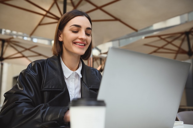 Piękna Kobieta Biznesmen, Copywriter, Programista, Freelancer, Dziennikarz Pracujący Zdalnie Na Laptopie, Piszący Tekst, Cieszący Się Odległą Pracą Na Zewnątrz Letniej Stołówki W Piękny Wczesnowiosenny Dzień