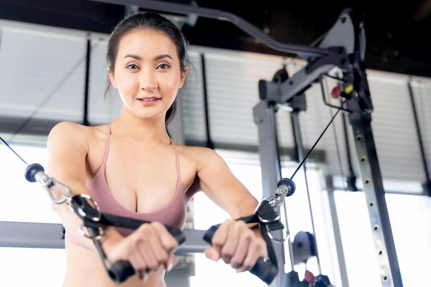 Piękna kobieta fitness slim fit w sportowej pracy ćwiczenia z kablem Crossover maszyny w sali fitness siłownia Asian sexy dziewczyna szczupłe ciało koncepcja modelu fitness