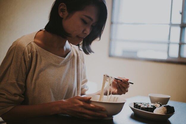 Zdjęcie piękna kobieta jedząca jedzenie siedząca w domu