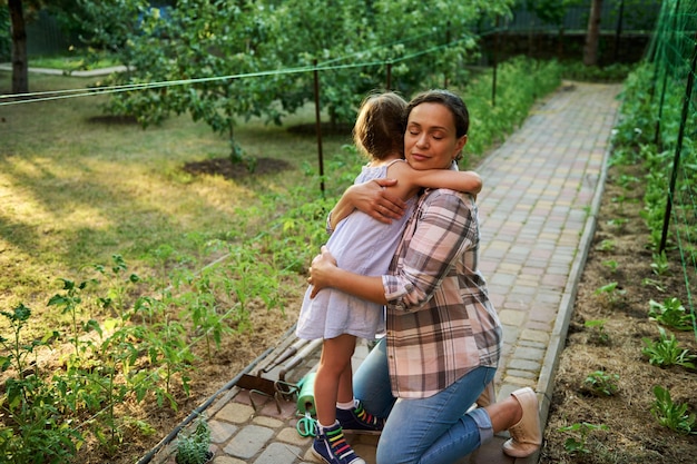Piękna kobieta matka przytulająca córkę stojąca razem w ekologicznej farmie podczas sadzenia i pielęgnacji sadzonek