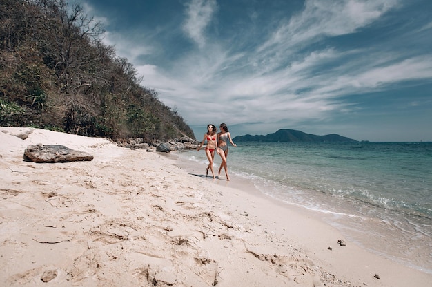 Piękna kobieta młoda para lesbijek w stroju kąpielowym w miłości spacery po plaży. Pojęcie społeczności LGBT, równe prawa, piękno i miłość. Phuket. Tajlandia. Piękny pejzaż morski.