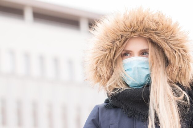 Zdjęcie piękna kobieta nosząca maskę na grypę patrząca w inną stronę, stojąc na zewnątrz
