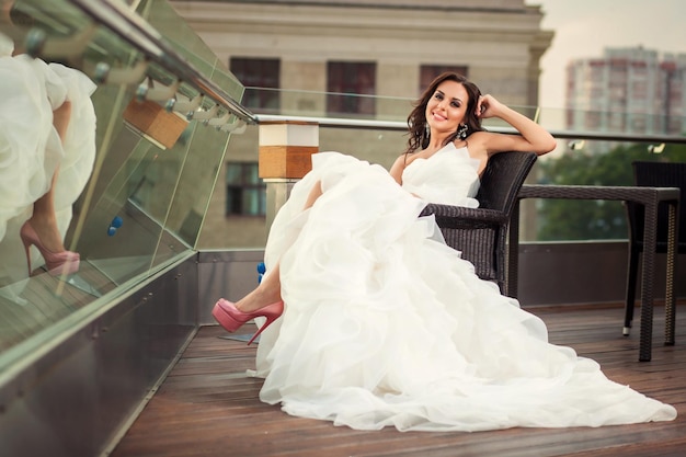 Zdjęcie piękna kobieta panna młoda w białej niesamowitej sukni ślubnej uśmiechnięta i siedząca na krześle
