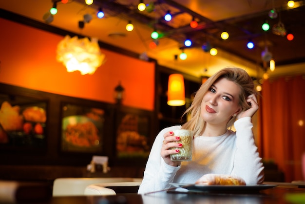 Piękna kobieta pije cappuccino w kawiarni