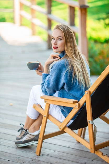 piękna kobieta pije kawę w parku jesień pod liście jesienią