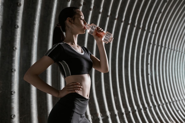 Piękna kobieta pije wodę z butelki po uruchomieniu