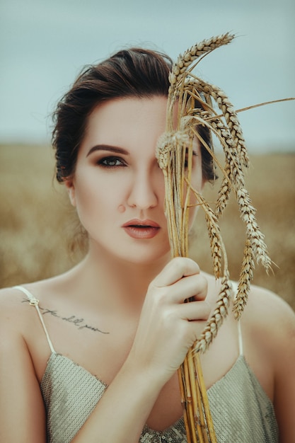 Piękna kobieta pozuje w polu pszenicy złotej