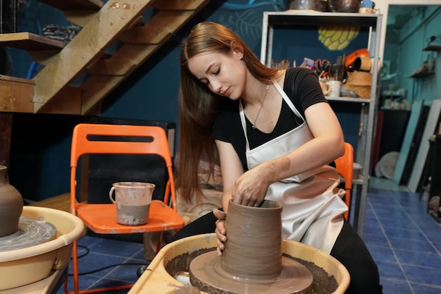 Zdjęcie piękna kobieta robi ceramikę ceramiczną na kole ręce zbliżenie kobieta w hobby freelance