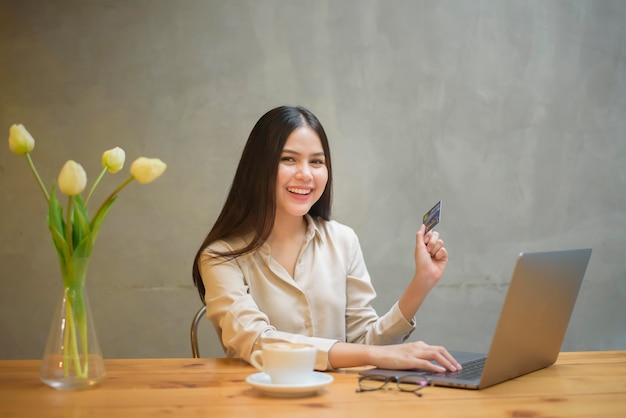 Piękna kobieta robi zakupy online za pomocą karty kredytowej w kawiarni