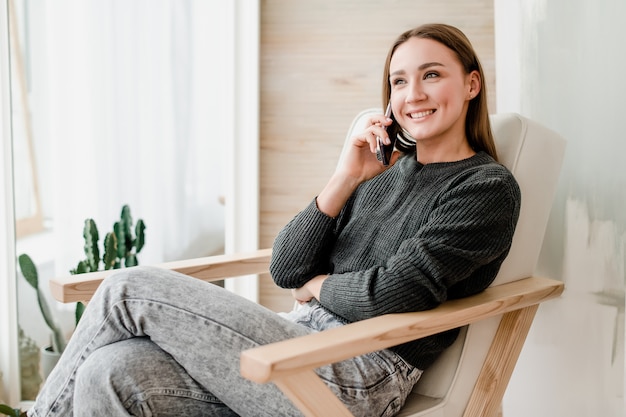 Piękna kobieta siedzi samotnie w krześle opowiada na telefonie