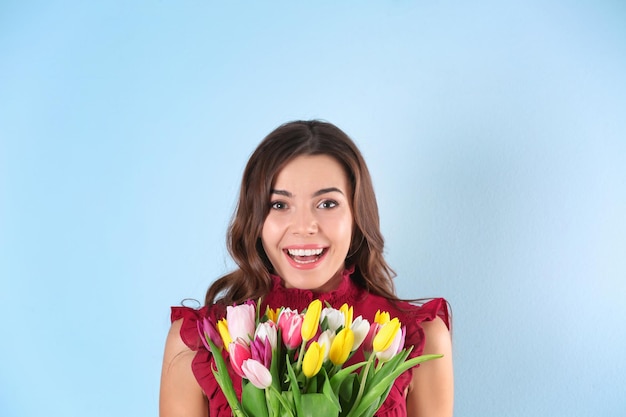 Piękna kobieta trzyma bukiet tulipanów na kolorowym tle