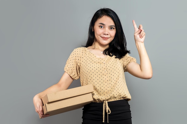 Piękna kobieta trzymająca jak pudełko po pizzy i wskazująca palcem w górę
