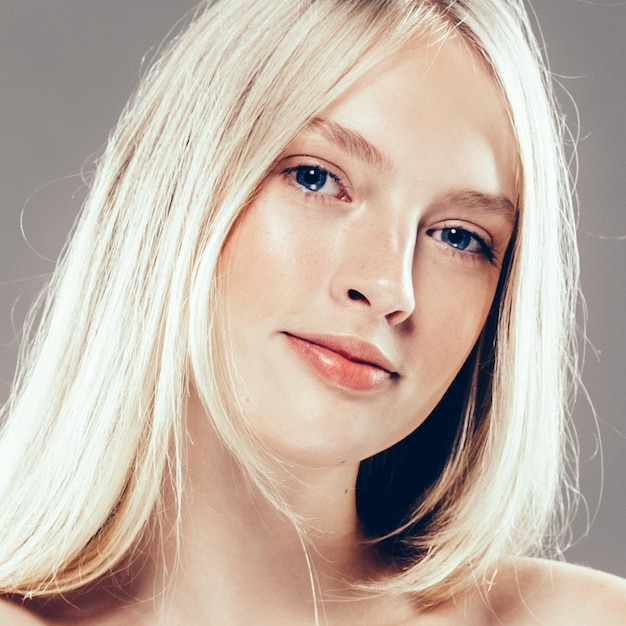 Piękna kobieta twarz portret uroda koncepcja pielęgnacji skóry z długimi blond włosami. Fashion Beauty Model z piękną fryzurą na szarym tle