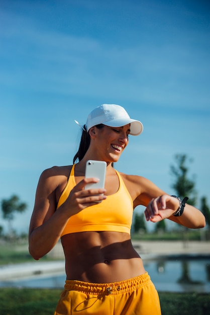 Piękna kobieta ubierał w sportach używać mobilnego telefon komórkowego.