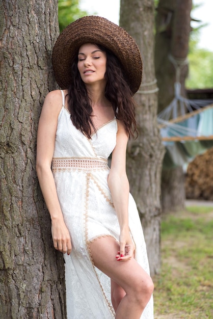 Piękna kobieta w białej letniej sukience i słomkowym kapeluszu