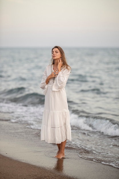 Piękna kobieta w białej sukni nad morzem