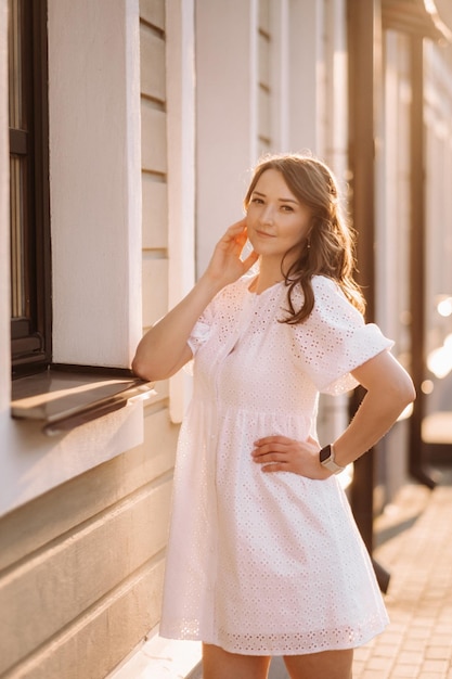 Piękna kobieta w białej sukni o zachodzie słońca w mieście Wieczorna fotografia uliczna