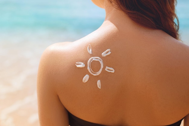 Piękna kobieta w bikini nakłada krem przeciwsłoneczny na twarz Kobieta z balsamem do opalania na plaży