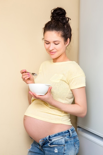 Piękna kobieta w ciąży o miskę jogurtu i owoców na lunch
