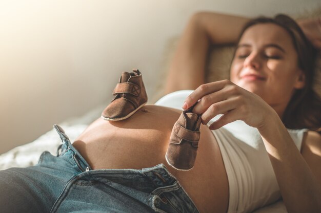 Piękna Kobieta W Ciąży Posiada Ubrania Dla Małego Dziecka. Szczęście. Pojęcie Ciąży