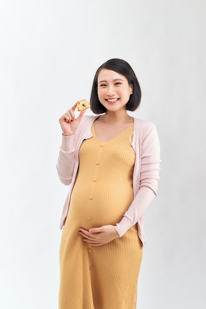 Piękna kobieta w ciąży trzyma smaczne ziarna chleba w swojej kuchni