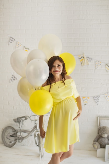 Piękna kobieta w ciąży w żółtej sukience w studio