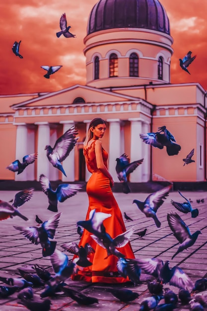 Piękna kobieta w czerwonej sukience z gołębiami w zachodzie słońca