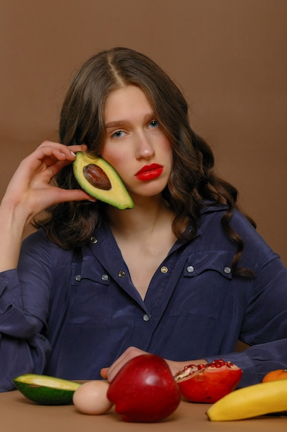 Piękna kobieta w czerwonej szmince pozuje z owocami