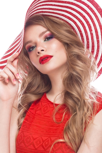 Piękna kobieta w kapeluszu z kolorowym makijażem, czerwonymi lokami i różowym manicure