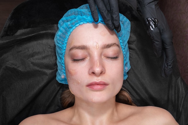 piękna kobieta w kosmetycznym salonie spa z maścią do masażu posmarowaną twarzą