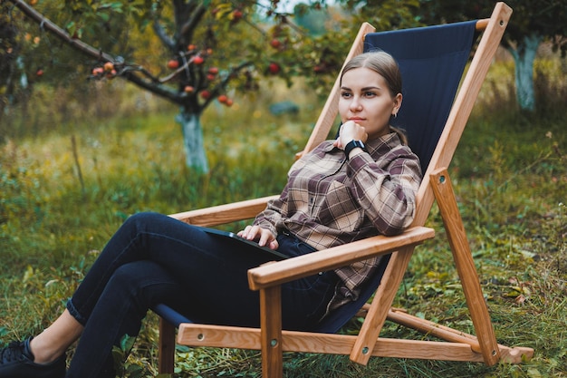 Piękna kobieta w kraciastej koszuli z laptopem pracującym na świeżym powietrzu w koncepcji domowego biura ogrodowego Praca zdalna