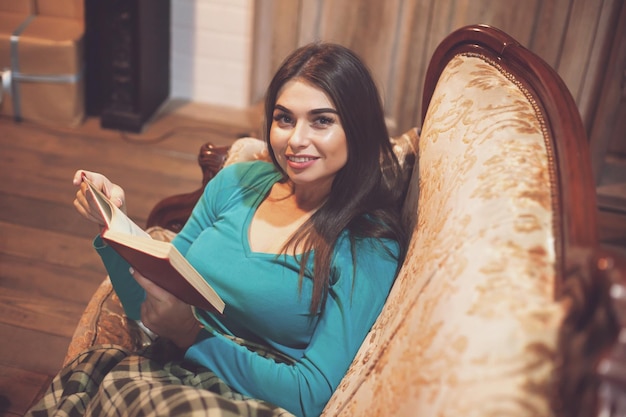 Piękna kobieta w kratę czyta czerwoną książkę na kanapie