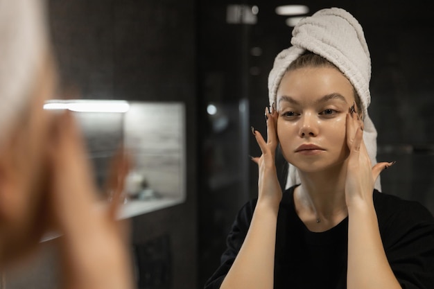 Piękna kobieta w łazience maluje twarz przed nałożeniem makijażu