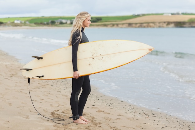 Piękna Kobieta W Mokrym Kostiumu Mienia Surfboard Przy Plażą