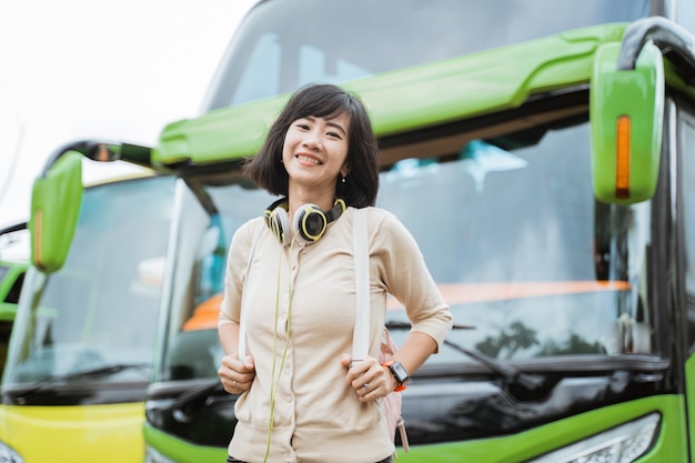 Piękna Kobieta W Plecaku I Słuchawkach Uśmiecha Się Na Tle Autobusu