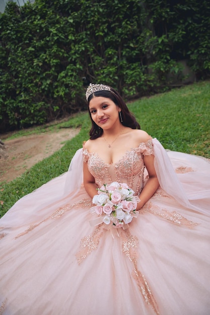 Piękna kobieta w różowym stroju księżniczki i bukiecie kwiatów na terenach zielonych
