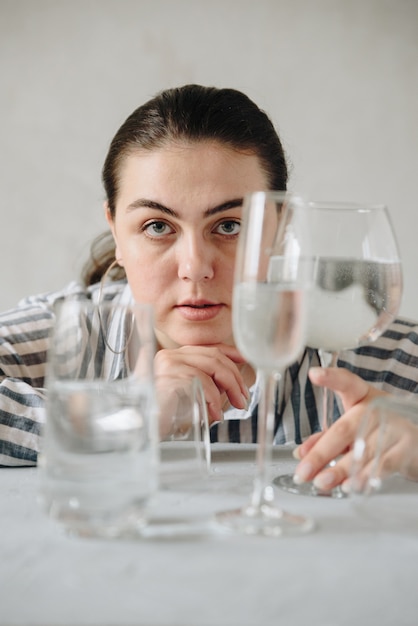 Piękna kobieta w szklankach wody na stole