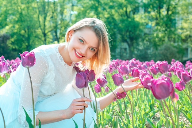 Piękna kobieta z kwiatami tulipanów w ogrodzie. Kobieta siedzi wśród kolorowych pól tulipanów.