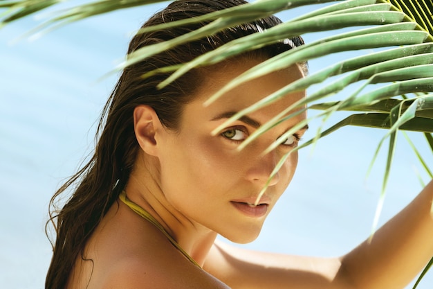Zdjęcie piękna kobieta z palmowym liściem na plaży