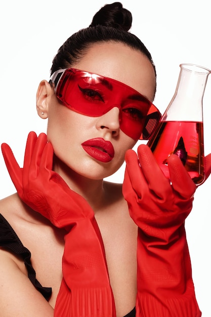 Zdjęcie piękna kobieta z pojemnikami laboratoryjnymi z czerwonym płynnym makijażem i fryzurą piękna twarz