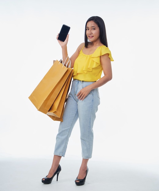 Piękna kobieta z torbami na zakupy i smartfonem