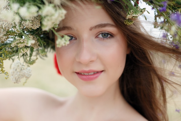 Piękna kobieta z wiankiem kwiatów na głowie. Piękna dziewczyna z fryzurą kwiatów. Dziewczyna w letnim lesie. Fotografia mody